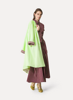 A model wearing an elasticated waist long skirt with deep burgundy red and lime green stripes, paired with a matching top and tan sandals.