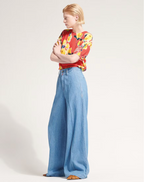 Person wearing a colorful shirt and blue jeans on a white background