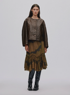 Model wearing a brown outfit with a jacket and skirt on a plain background