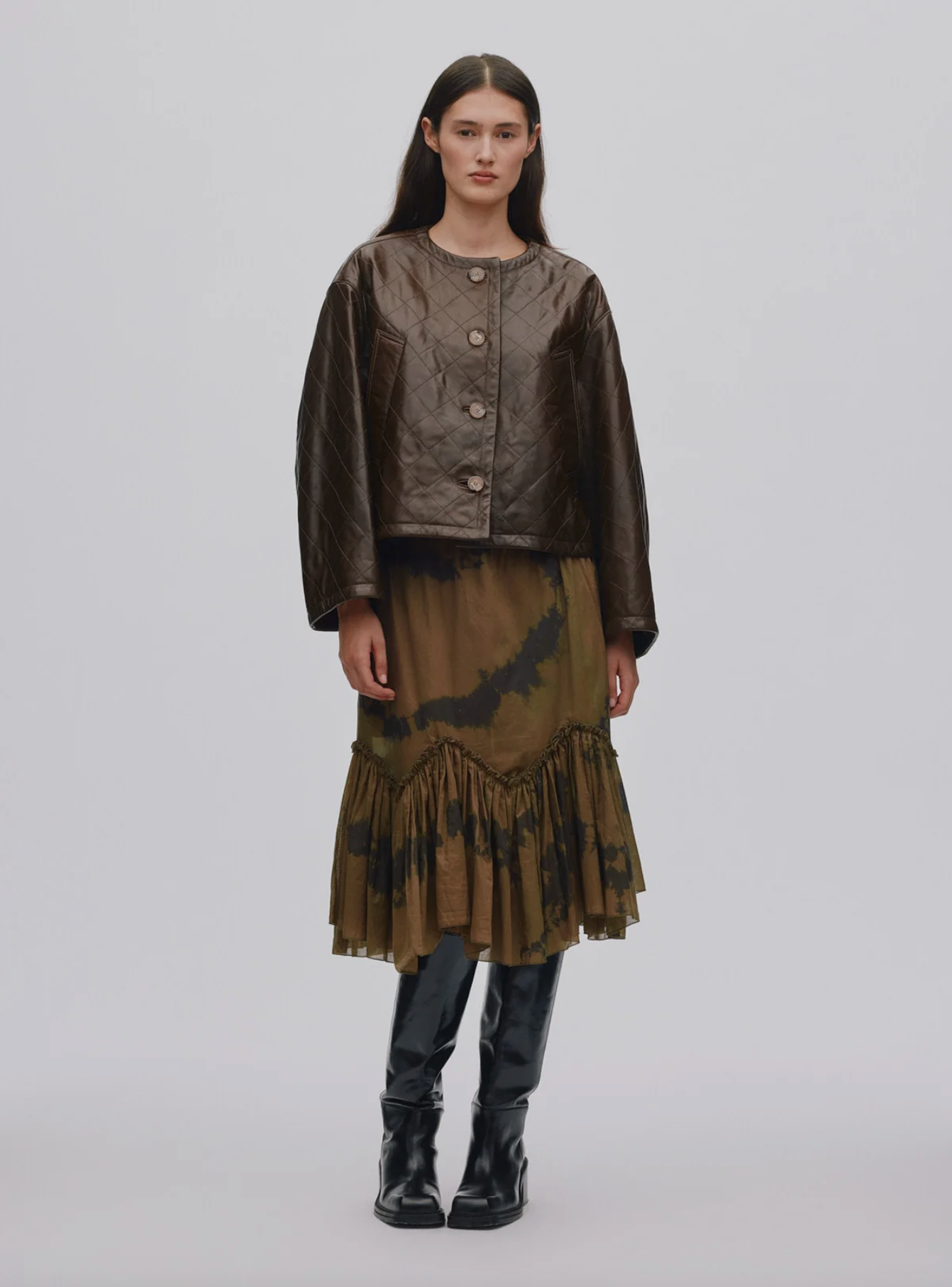 Model wearing a brown outfit with a jacket and skirt on a plain background