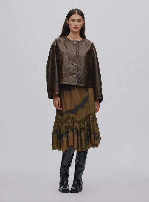 Model wearing a brown outfit with a jacket and skirt on a plain background