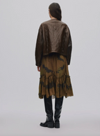 Person wearing a long, dark brown coat with a patterned skirt on a white background