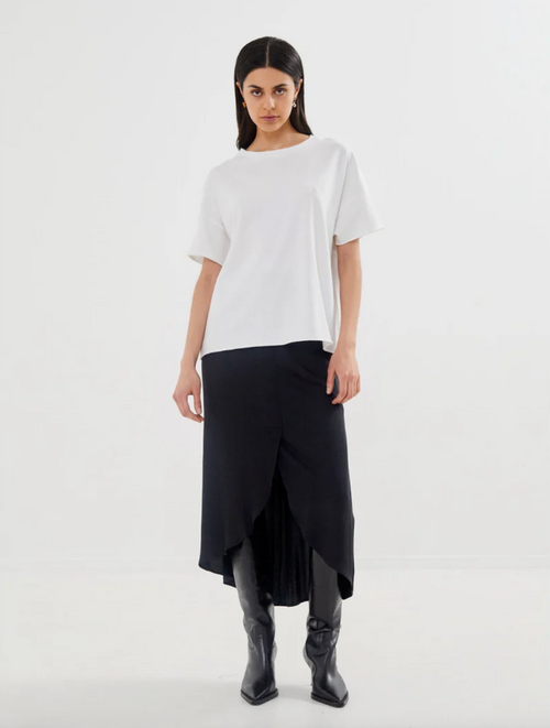Woman wearing a white top and black skirt on a white background