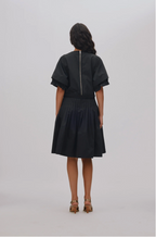 Person wearing a black dress with a zipper detail on a white background
