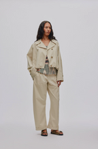 Woman wearing a beige jacket and pants on a white background
