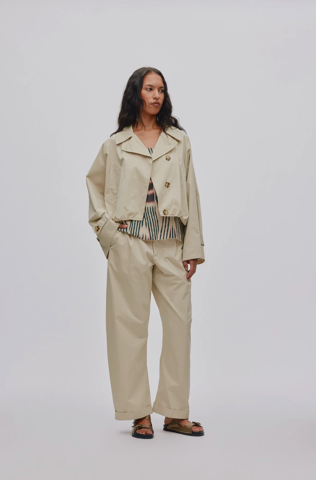 Woman wearing a beige jacket and pants on a white background