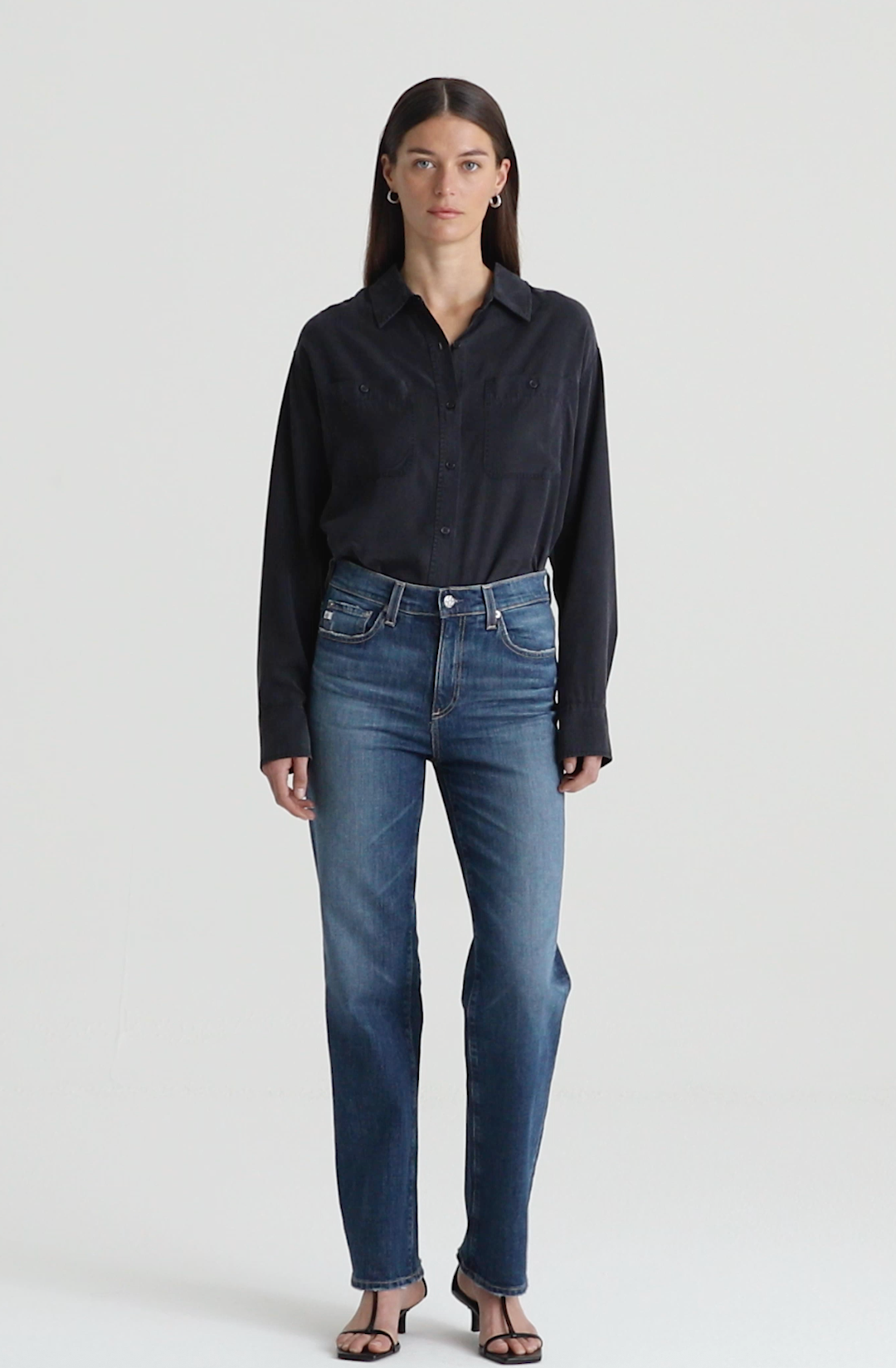 A female model wearing a black shirt and mid-rise straight denim jeans with a vintage look.