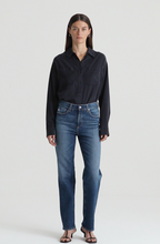 A female model wearing a black shirt and mid-rise straight denim jeans with a vintage look.
