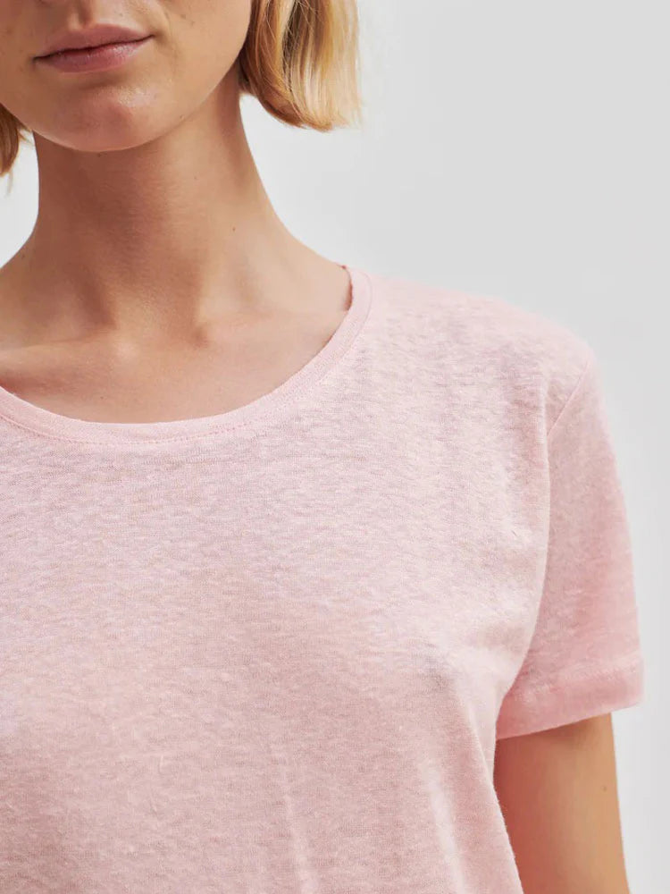 Close-up of a person wearing a light pink t-shirt against a neutral background