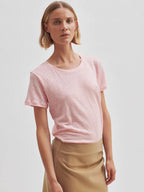Woman wearing a second female pink linen t-shirt and beige pants against a plain background