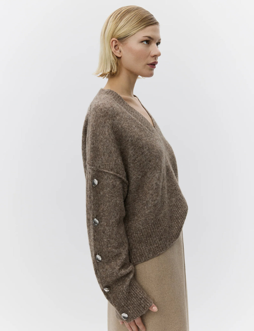 Woman wearing a brown sweater with button details on a white background