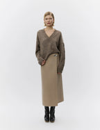 Woman wearing a brown sweater and beige skirt on a white background