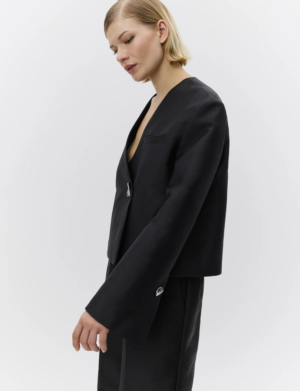 Person wearing a black suit on a plain background