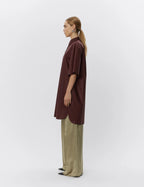 Person wearing a brown shirt and beige pants on a white background