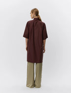 Person wearing a brown shirt and beige pants on a white background