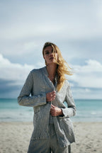 Woman in a striped suit standing on a beach with ocean and sky in the background