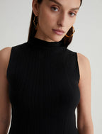 A person wearing a black funnel-neck top with a sleeveless design, made from a soft variegated rib knit.