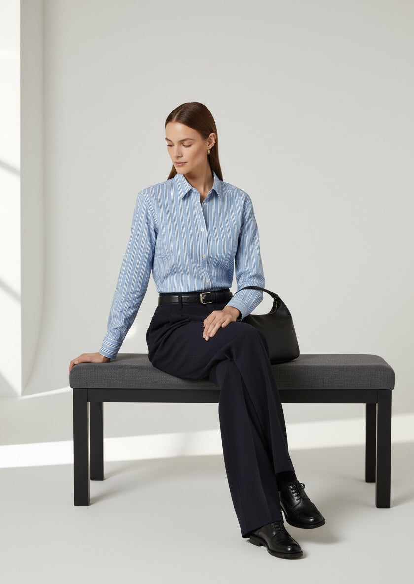 Woman sitting on a bench wearing a light blue striped shirt and black pants. weekend Max Mara bahamas shirt 