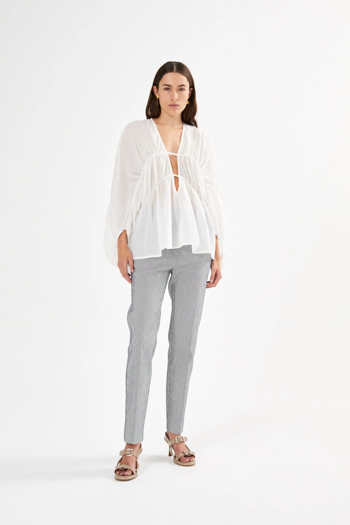 Woman wearing a white blouse and gray pants on a white background