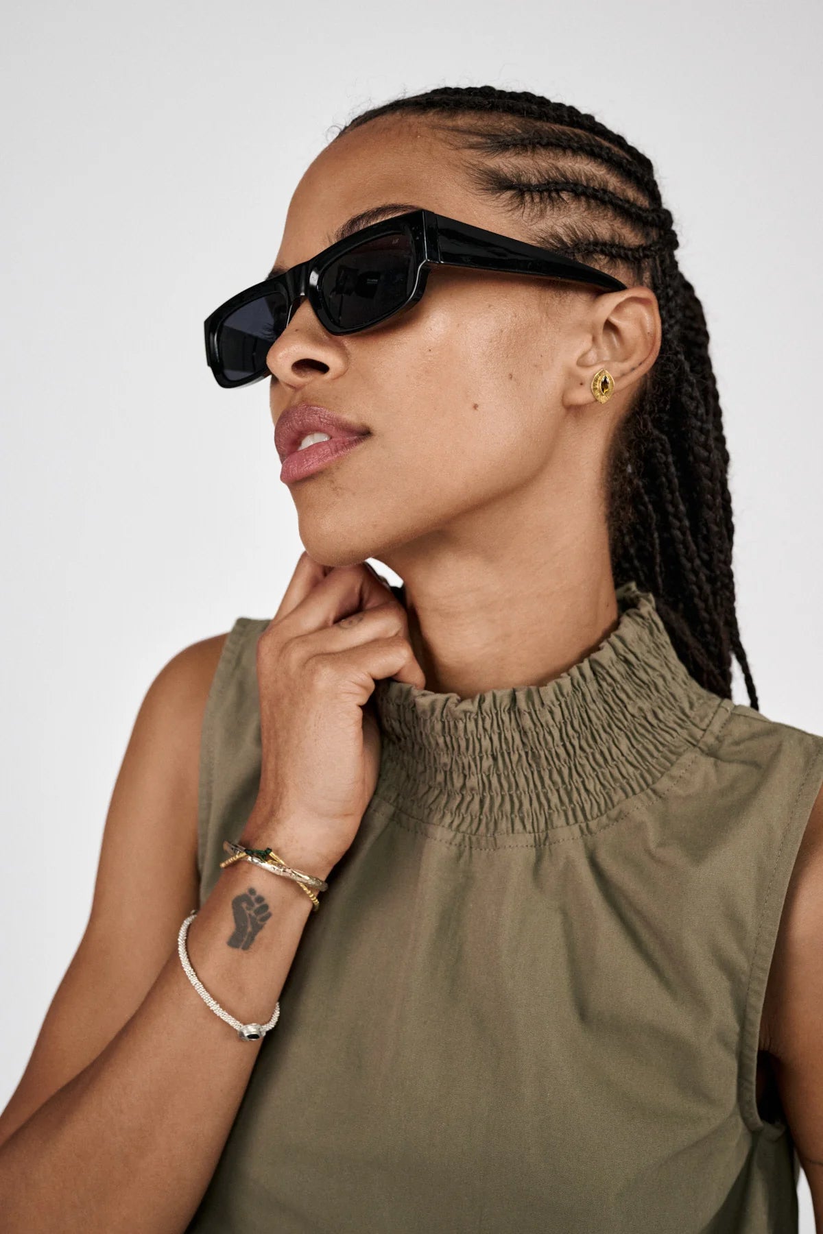 Woman wearing sunglasses and a green sleeveless top against a white background