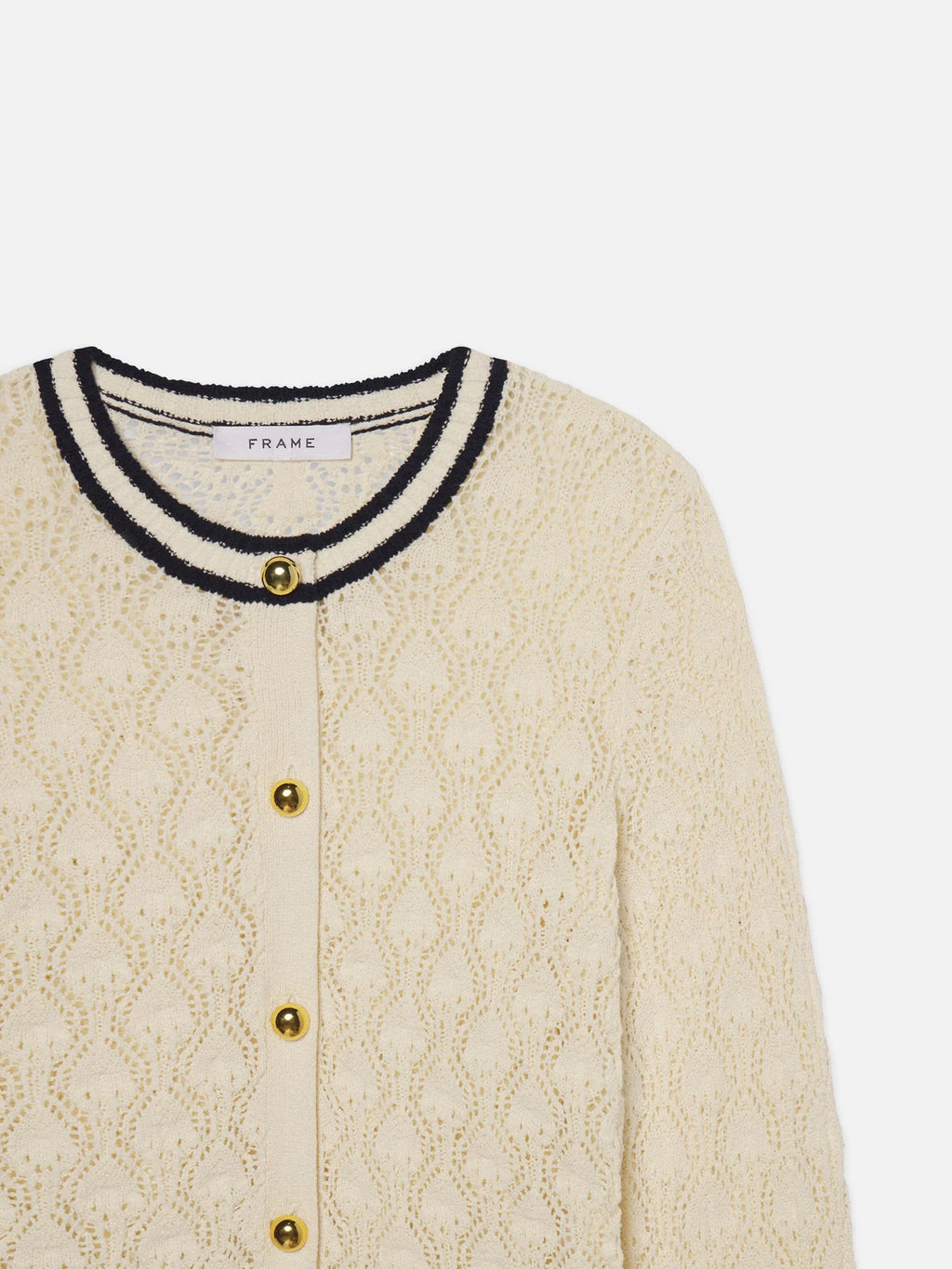 Cream-colored cardigan with black trim and gold buttons on a white background