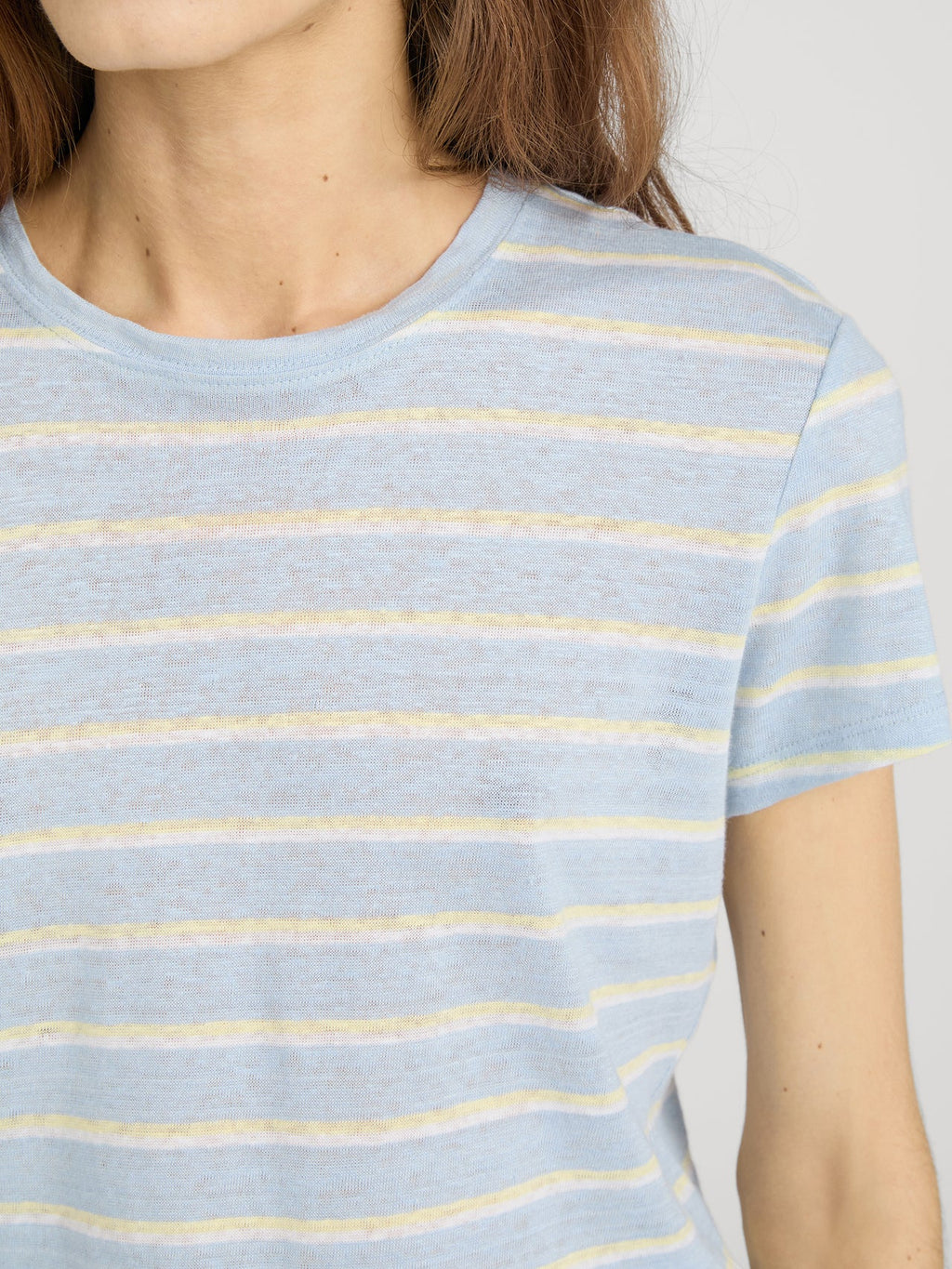 Close-up of a person wearing a light blue and yellow striped shirt against a neutral background