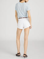 Person wearing a striped shirt and white shorts on a plain background