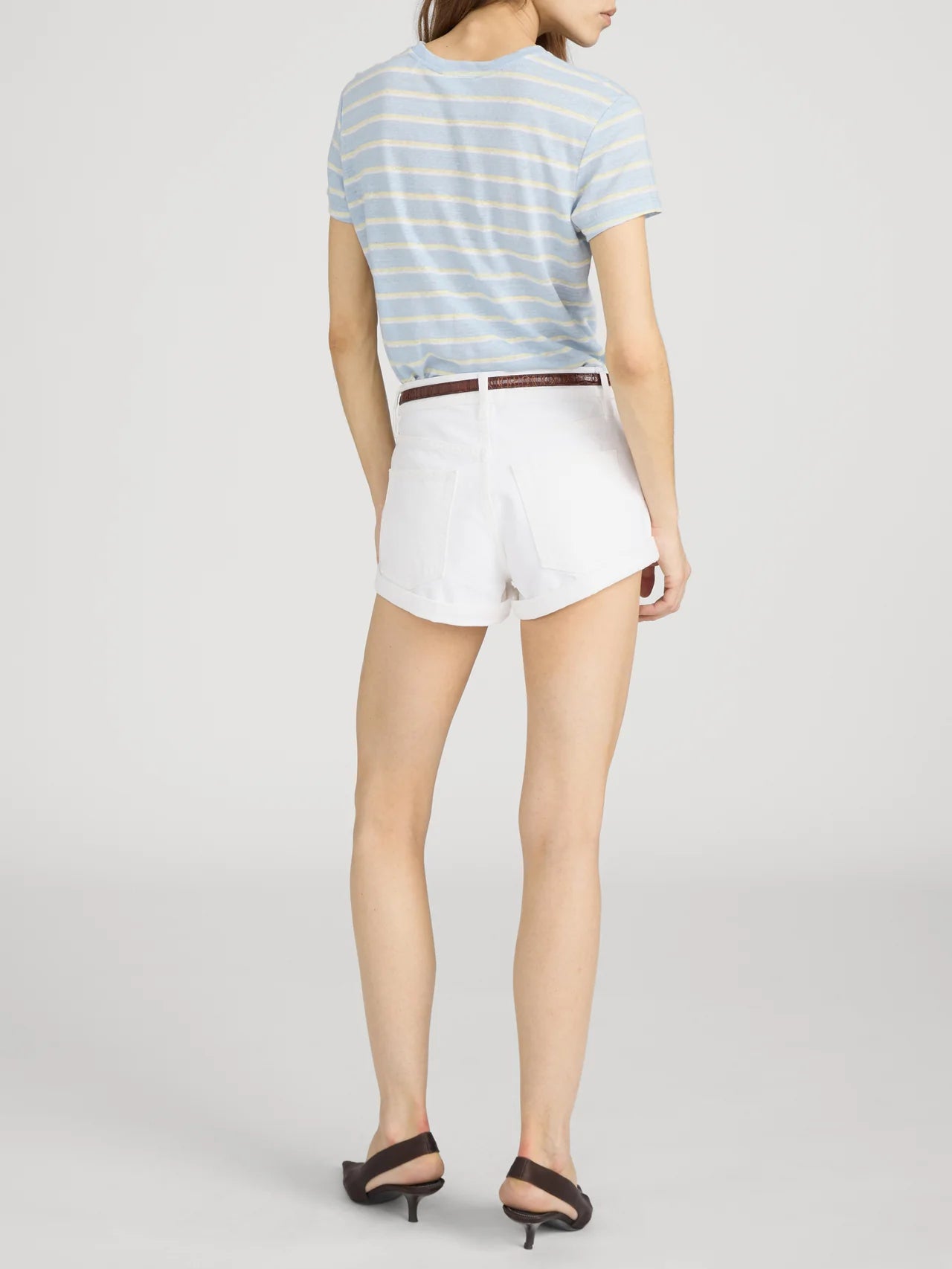 Person wearing a striped shirt and white shorts on a plain background