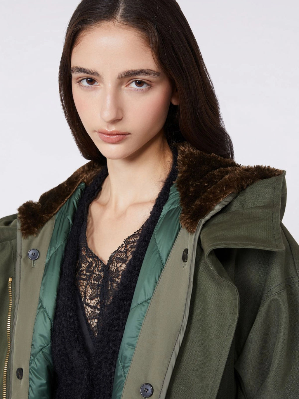Woman wearing a green coat with fur trim on a white background