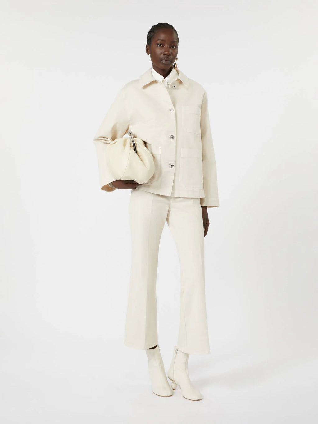 Person wearing a white outfit holding a matching handbag on a white background