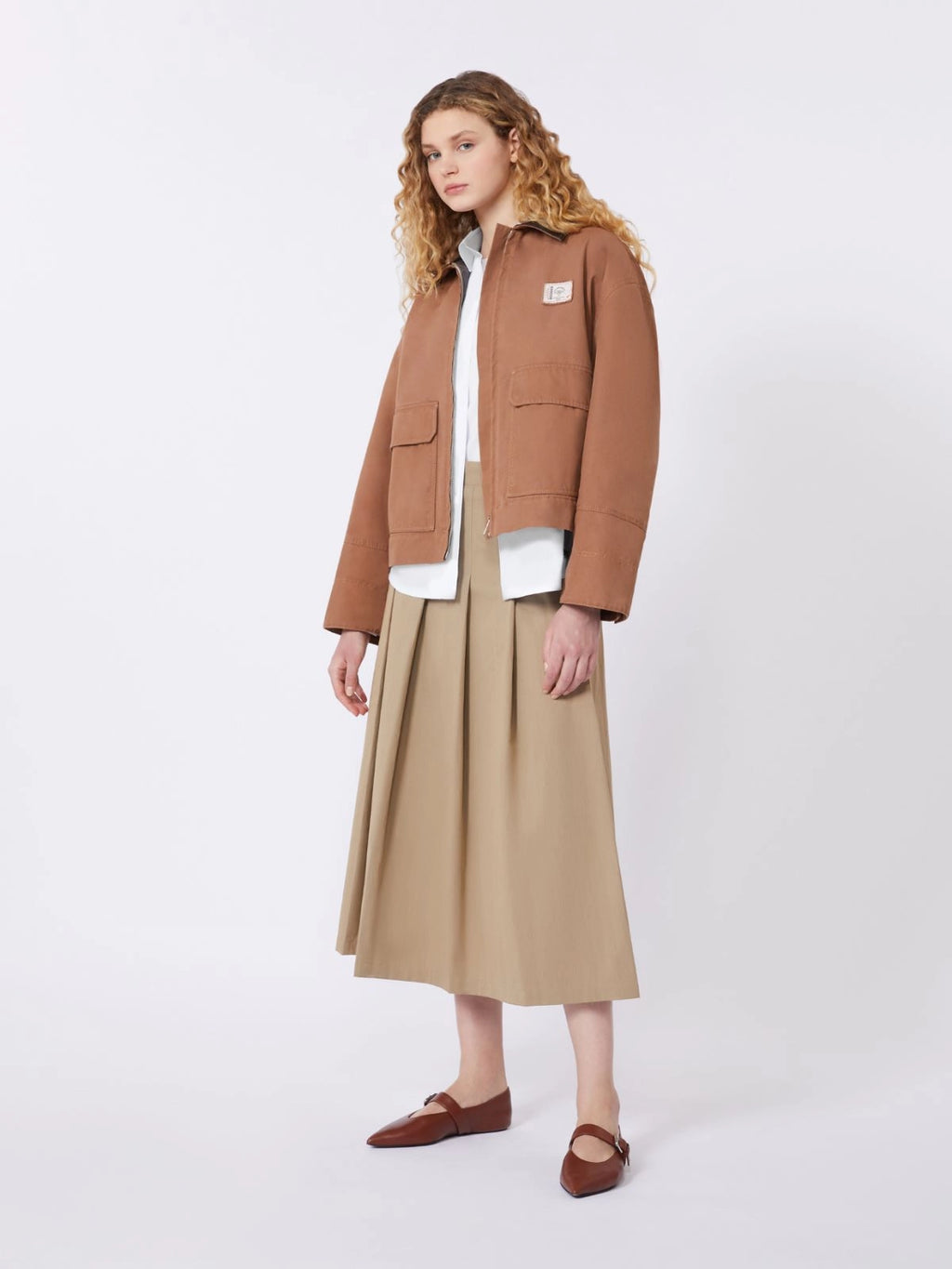 Woman wearing a brown jacket and beige skirt on a white background