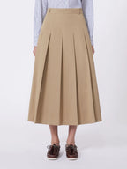 Person wearing a beige pleated skirt on a white background
