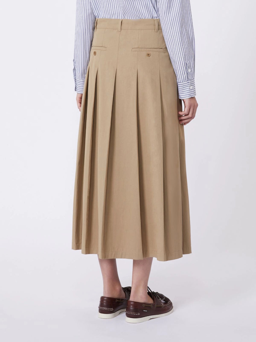 Person wearing a beige pleated skirt with a white background