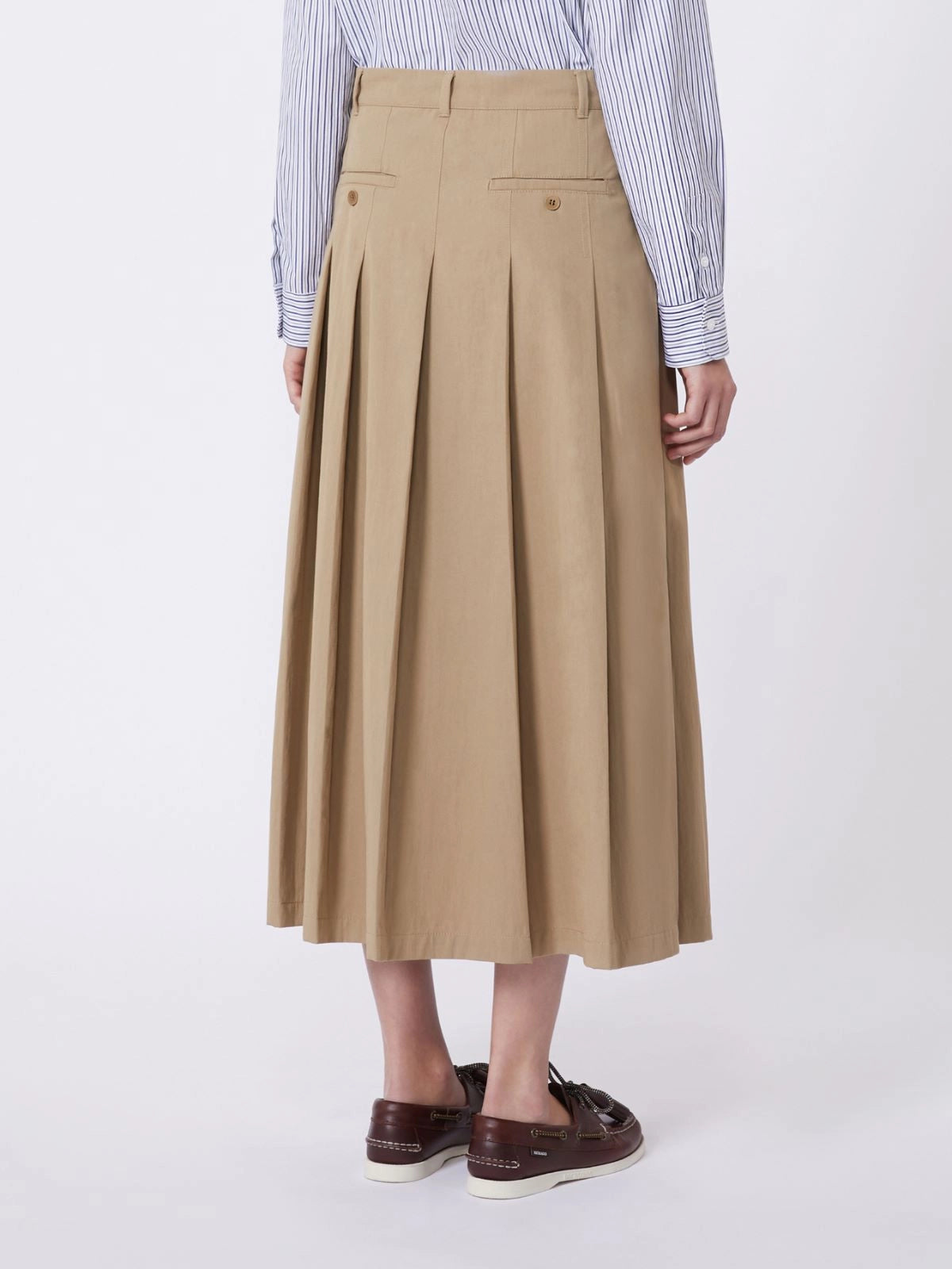 Person wearing a beige pleated skirt with a white background