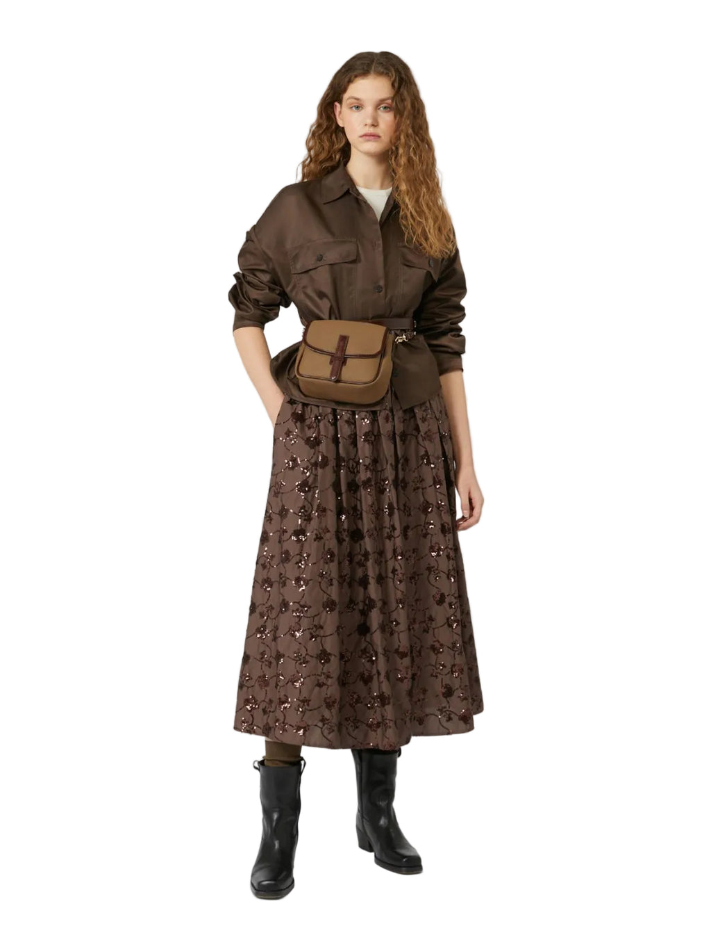 Woman wearing a brown outfit with a patterned skirt and jacket on a white background