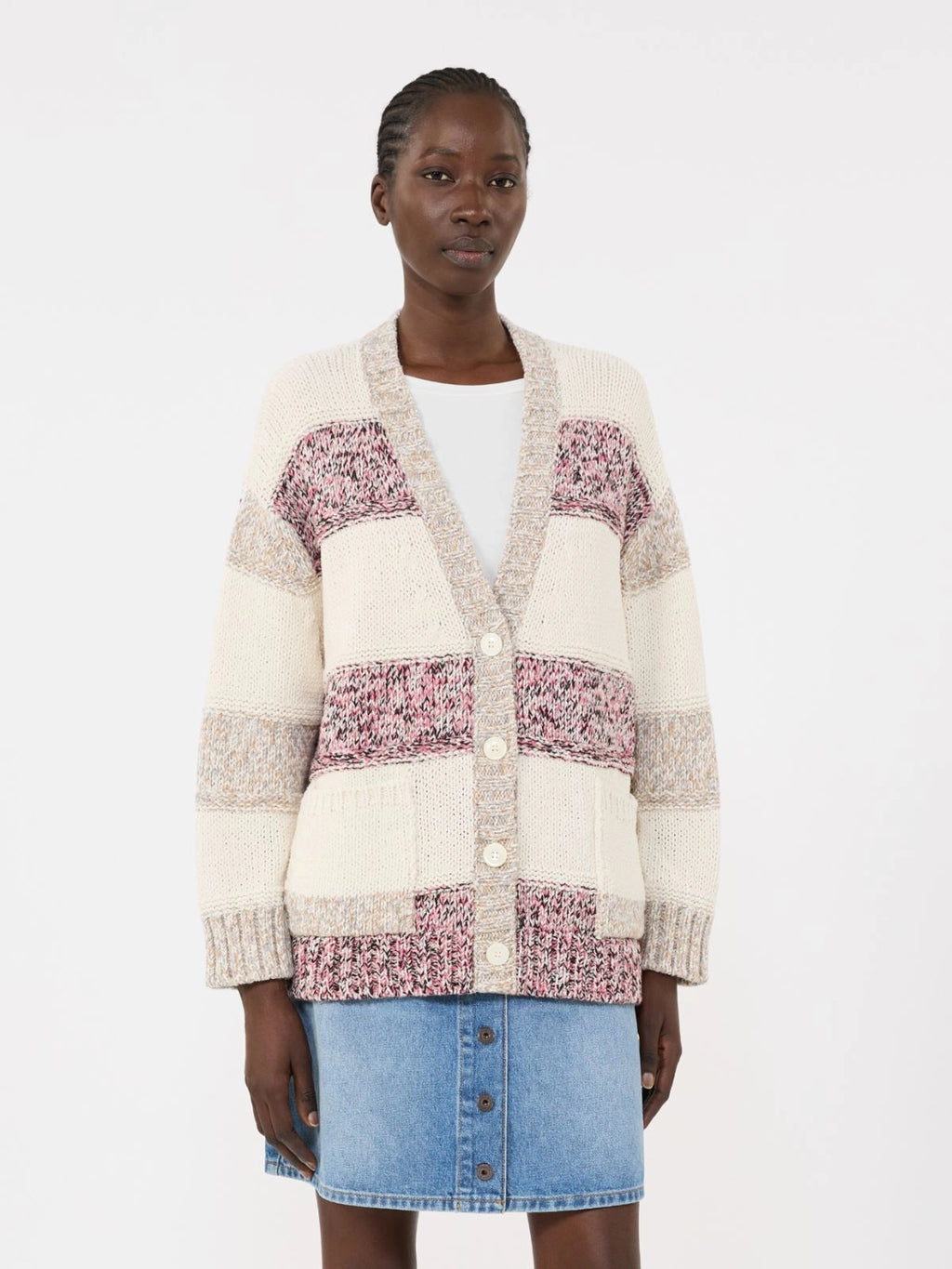 Woman wearing a patterned cardigan over a white shirt with a blue denim skirt on a white background