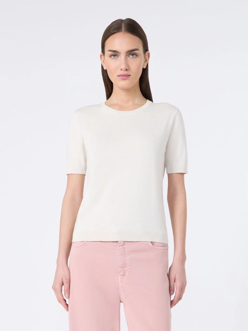 Woman wearing a white t-shirt and pink pants on a white background
