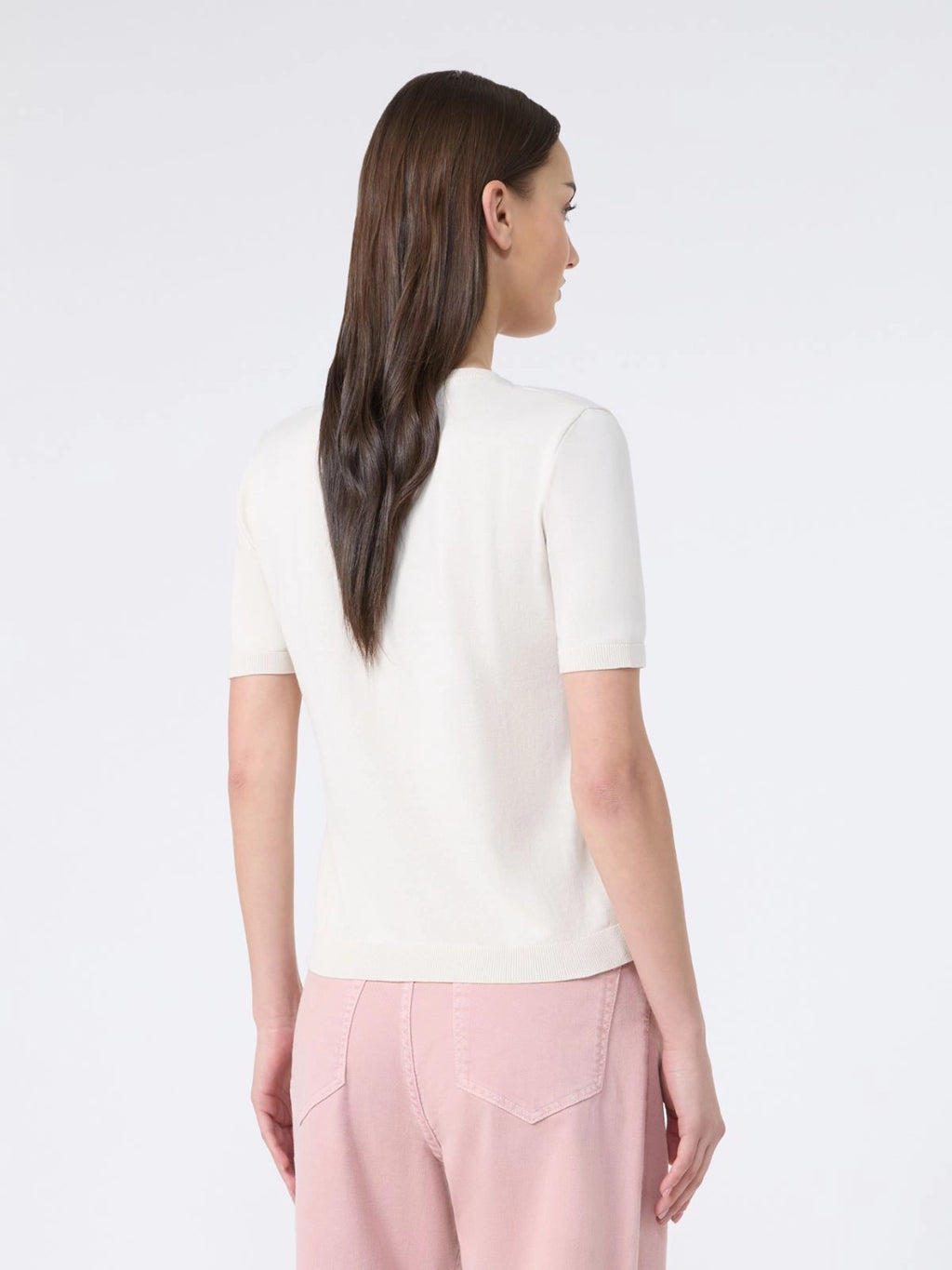 Woman wearing a white top and pink pants on a white background