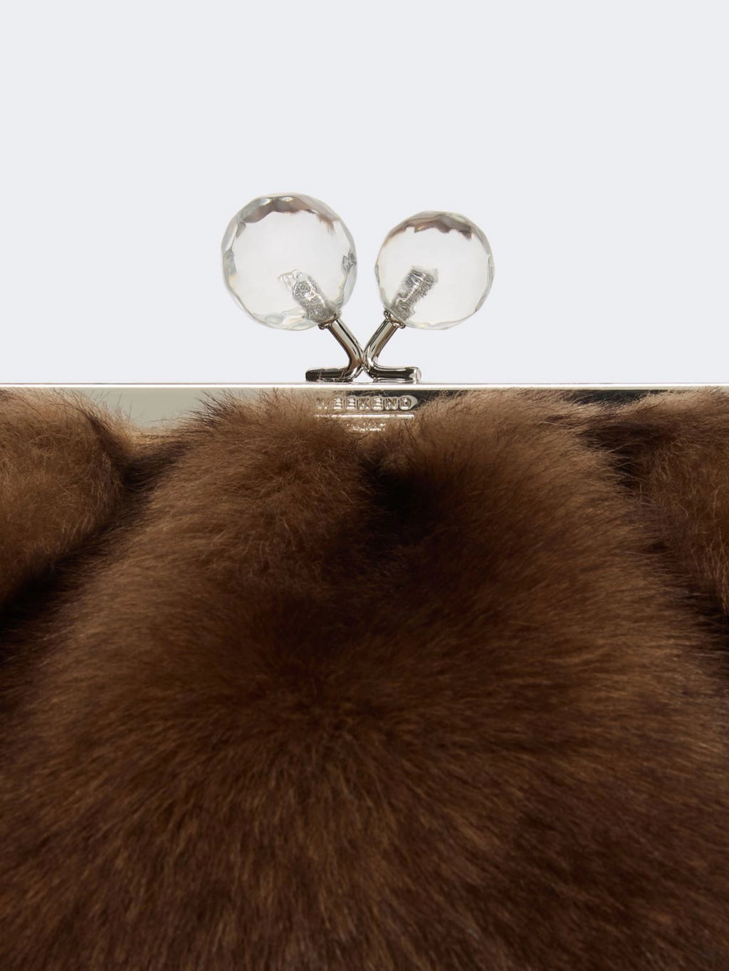 Brown fur clutch with a metallic clasp on a light gray background