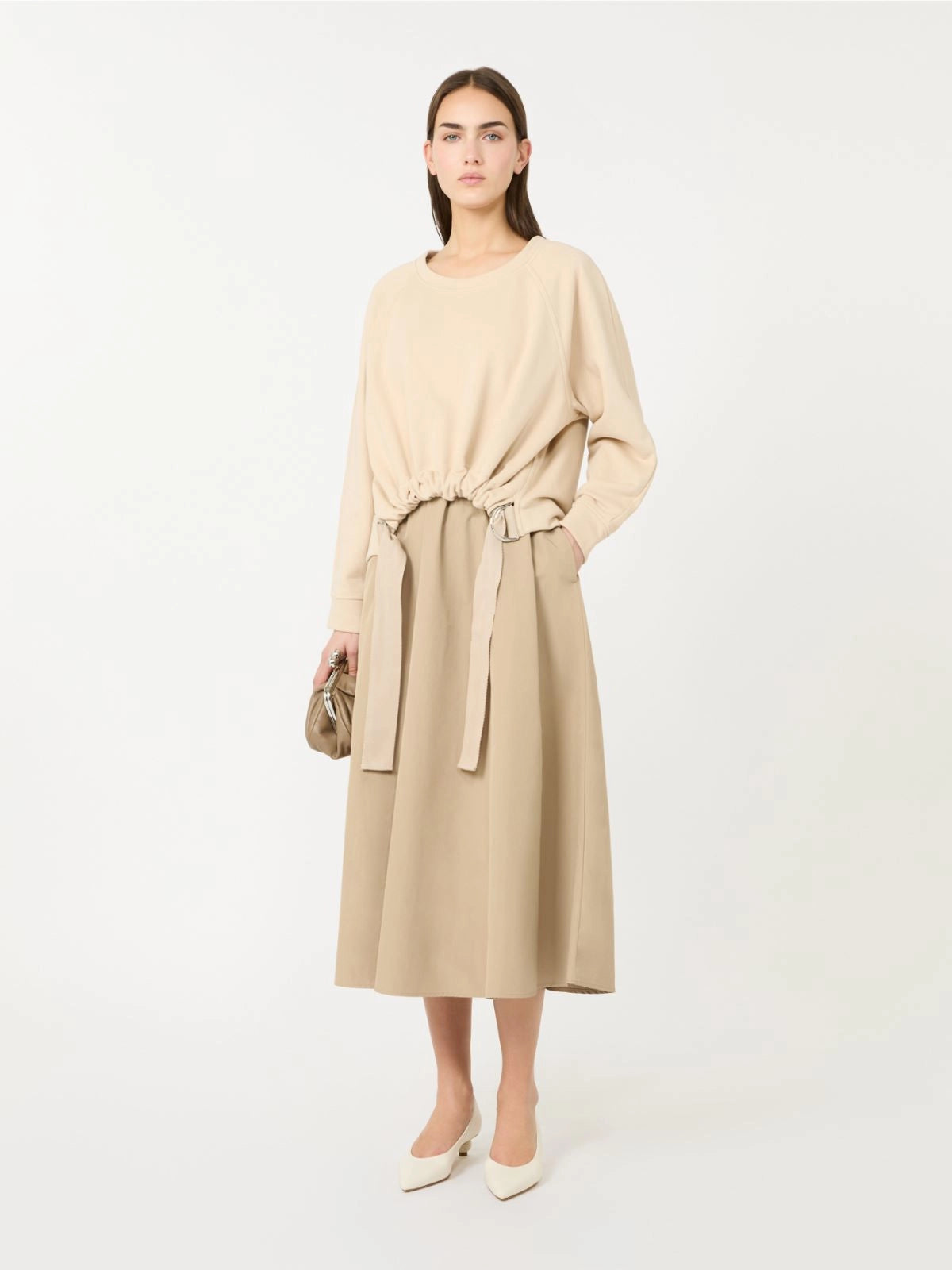 Woman wearing a beige dress with a belt on a white background