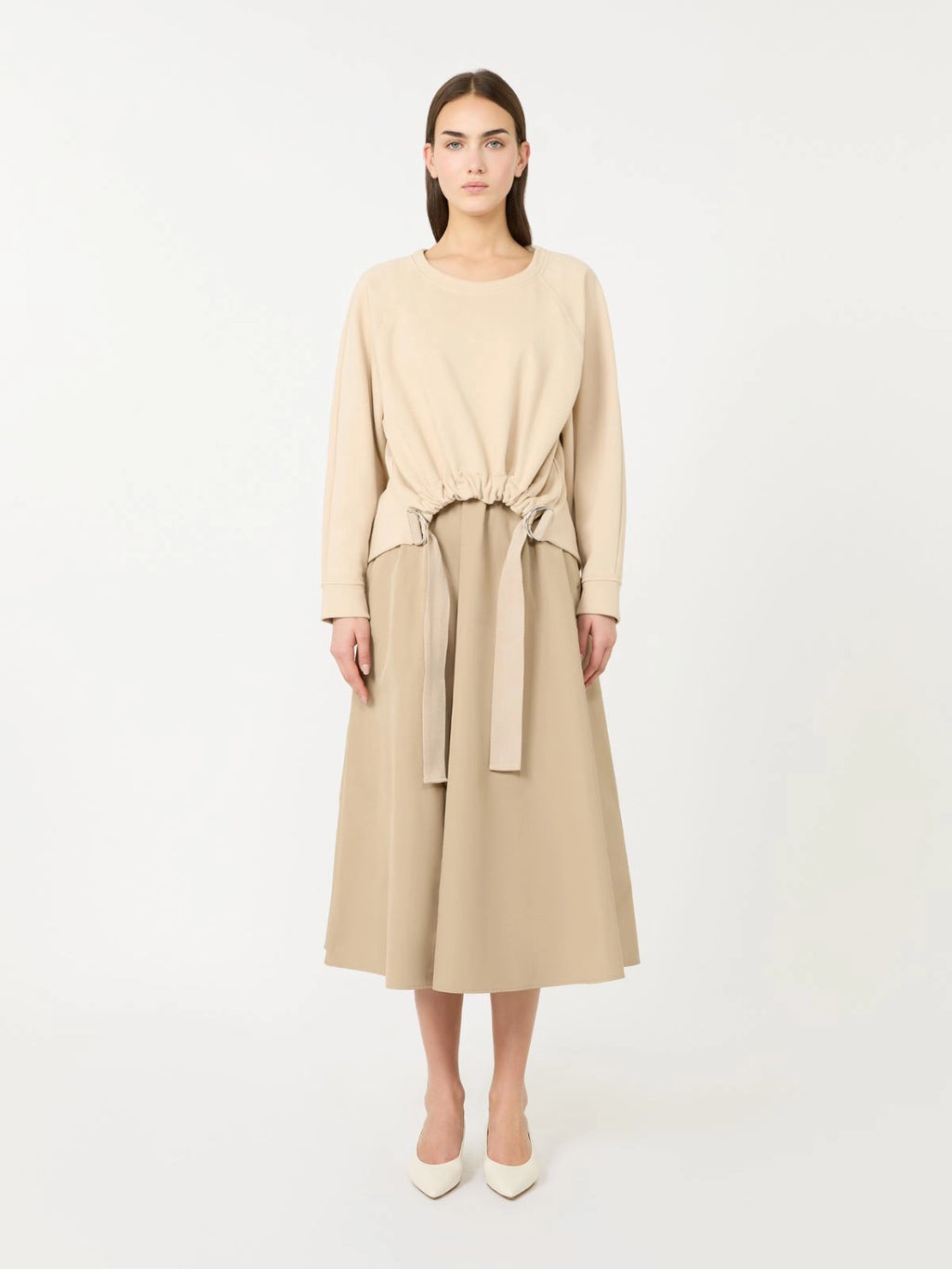 Woman wearing a beige dress with a belt on a white background