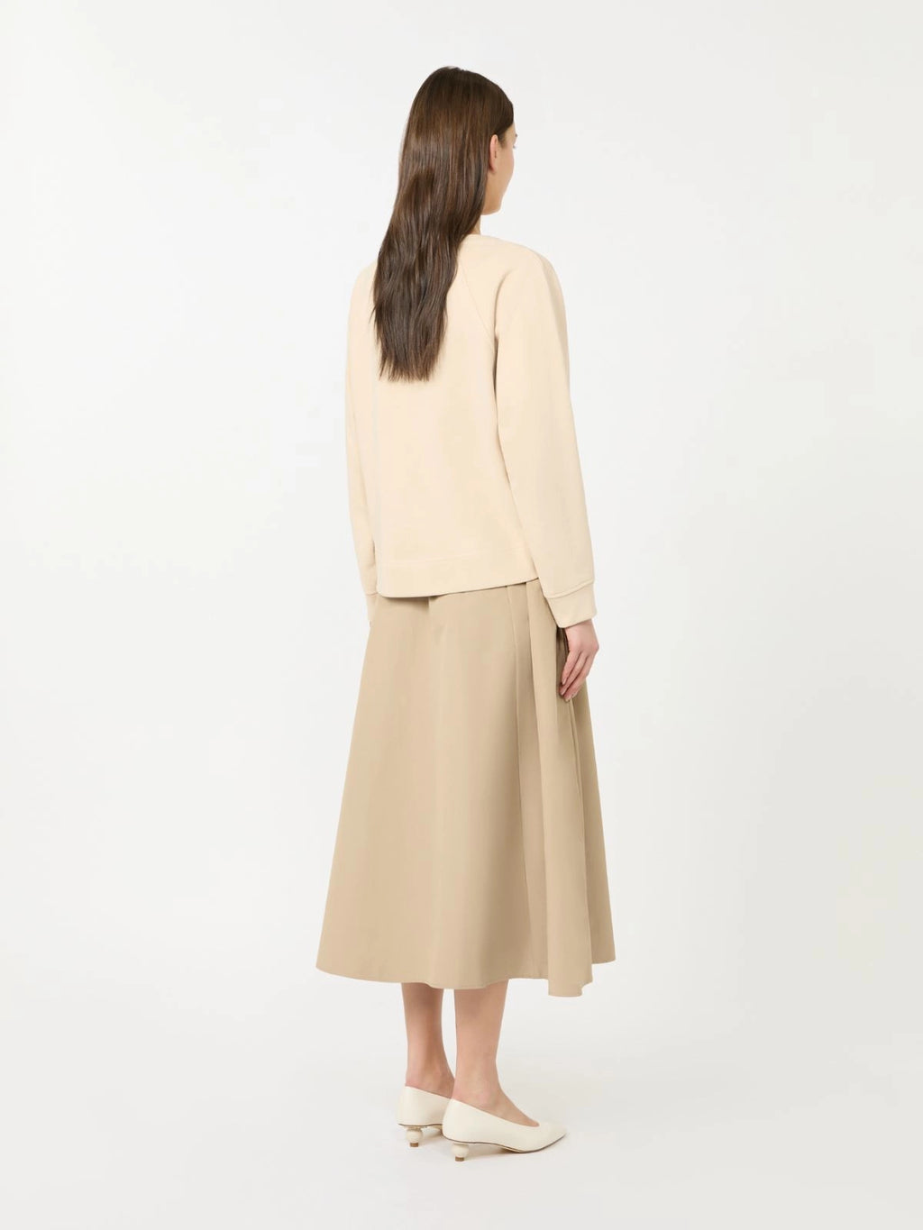 Woman wearing a beige top and beige skirt on a white background