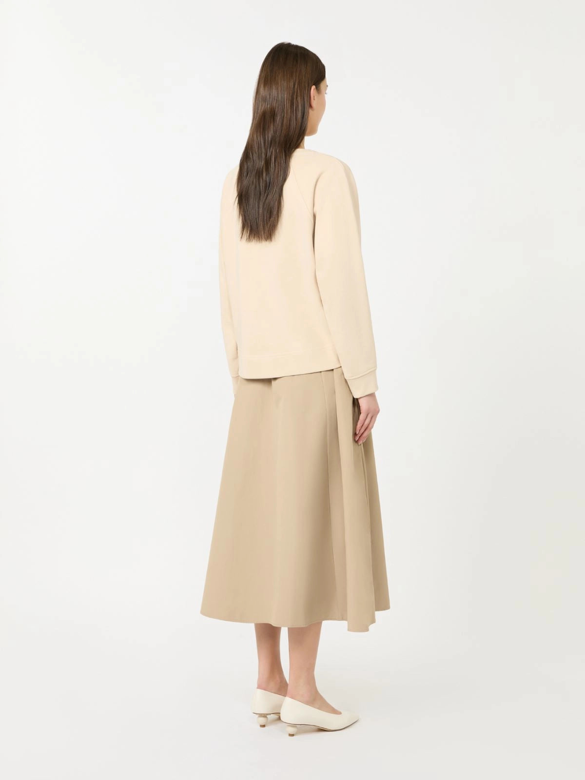 Woman wearing a beige top and beige skirt on a white background