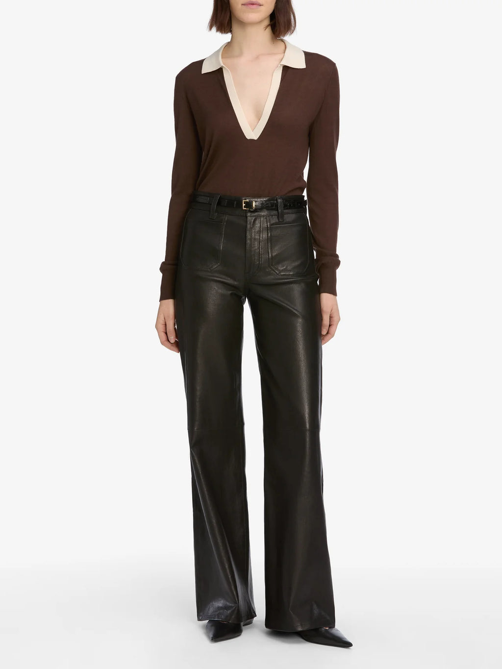 Person wearing a brown long-sleeve top and black leather pants on a white background