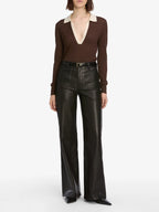 Person wearing a brown long-sleeve top and black leather pants on a white background