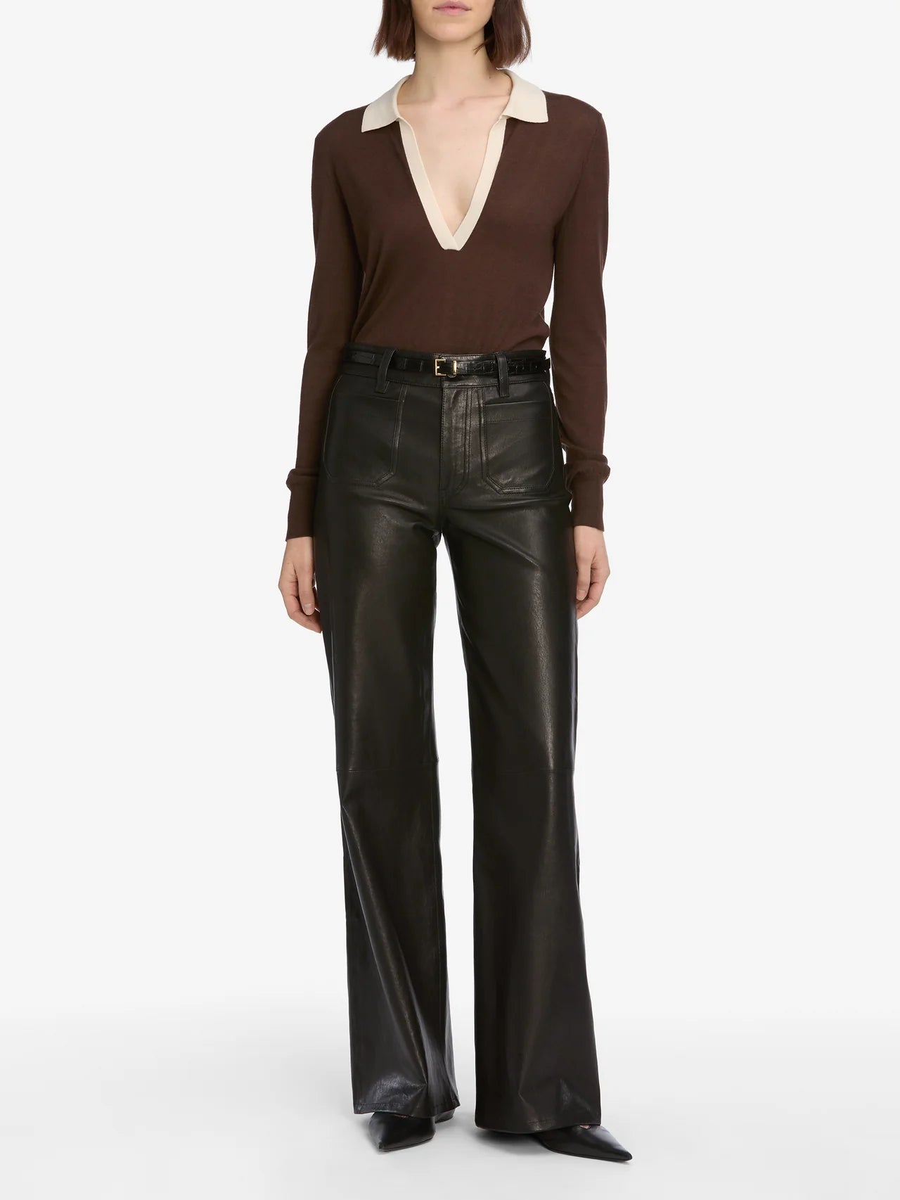 Person wearing a brown long-sleeve top and black leather pants on a white background