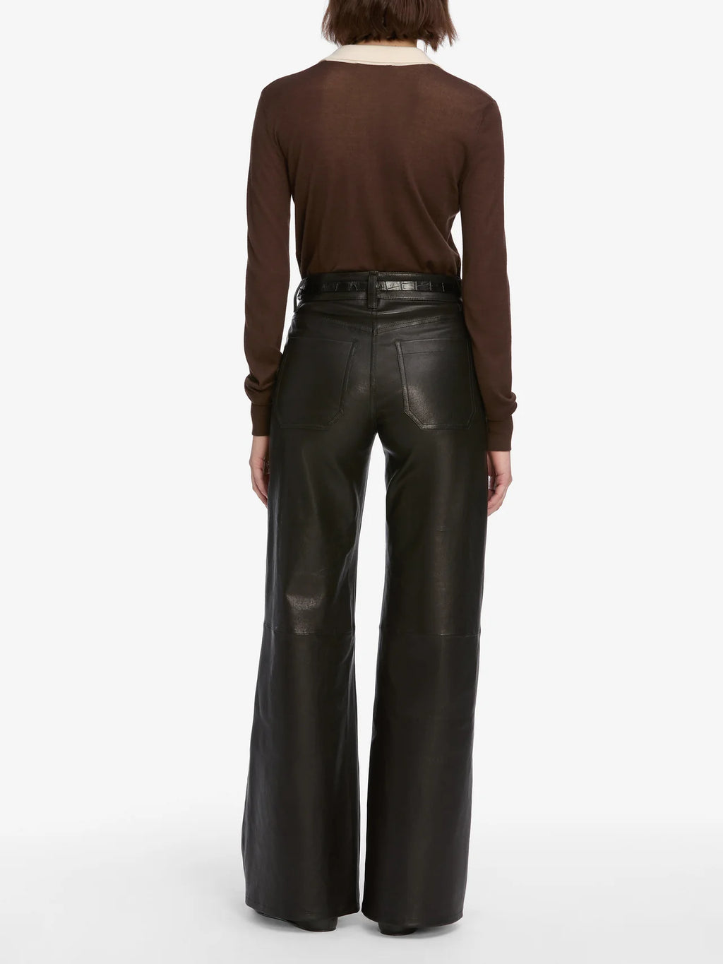 Person wearing brown long-sleeve top and black leather pants on a white background