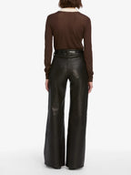 Person wearing brown long-sleeve top and black leather pants on a white background