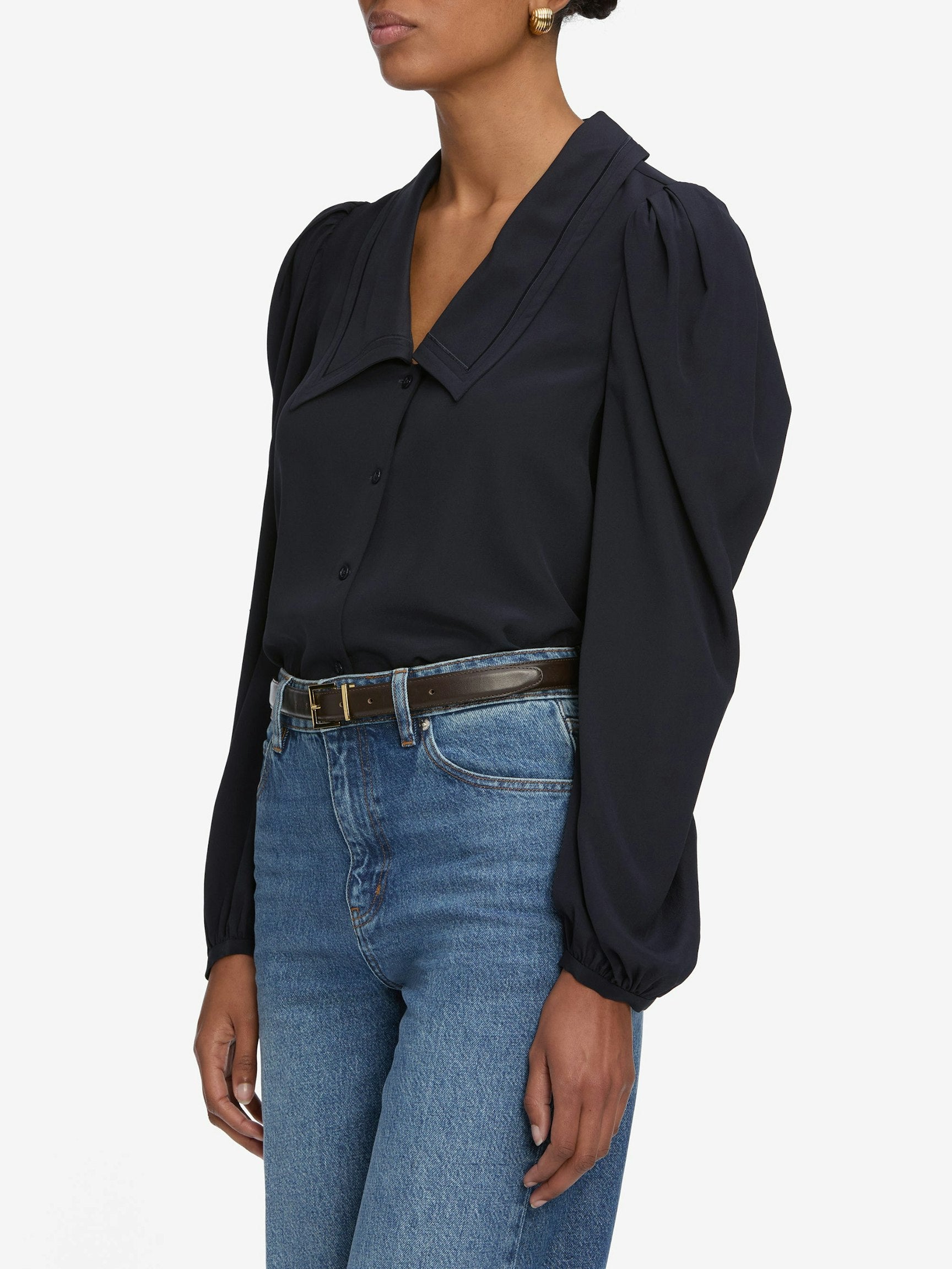 Person wearing a navy blouse and blue jeans on a white background