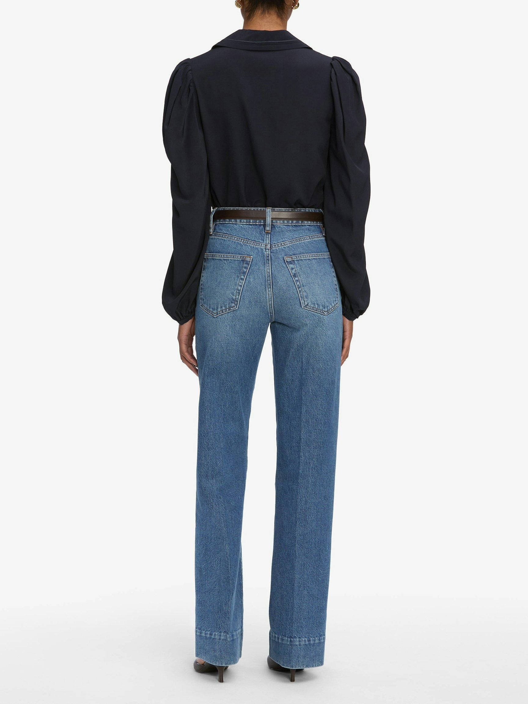 Person wearing blue jeans and a navy top on a white background